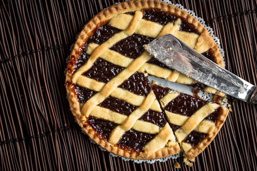 A lattice pie with a slice cut out of it and a knife sitting on top.