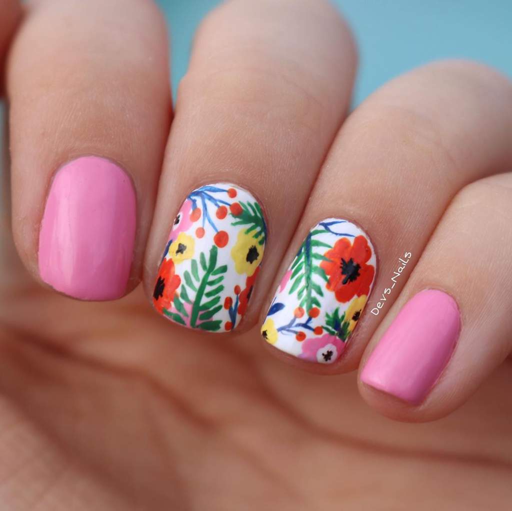Painted fingernails, two are bright pink and two have painted flower patterns.