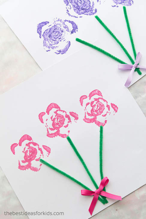 Paper with pink and purple stamped rose designs, green pipe-cleaner stems and pink and purple ribbons around the stems.