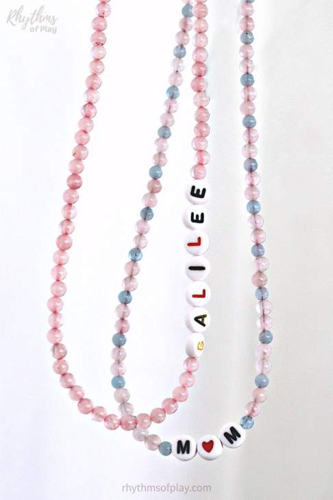Two bead necklaces - one is pink and has beads spelling out GALILEE and the other is pink and blue and spells out MOM with a heart instead of the O.