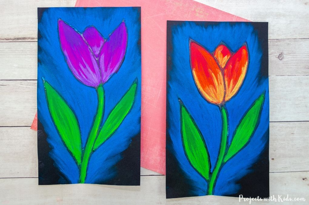 Two pastel drawings of tulips, a purple one on the left and a yellow and red one on the right, each with a blue background on black paper.