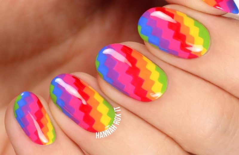 Fingernails with brightly colored pixellated rainbow pattern